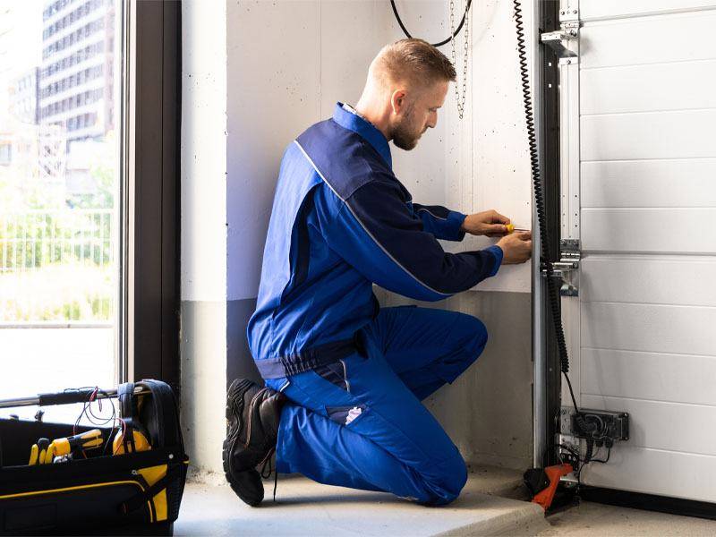 A garage door service tech works on a spring segment. Garage door installation and repair is Grand River Garage Door's forte.