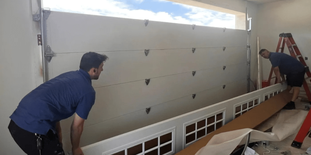 Two men install garage door panel frame.